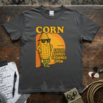 Corn – ’Cause Porn Is Frowned Upon Shirt on a wooden table with guitar picks and music notes.