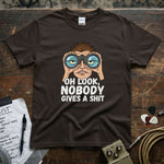 Oh Look, Nobody Gives a Shit Shirt featuring a graphic of a person with binoculars on a brown tee.