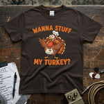 Wanna Stuff My Turkey Shirt featuring a cartoon turkey chef on a brown t-shirt with vibrant orange text.