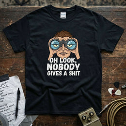 Oh Look, Nobody Gives a Shit Shirt featuring a character with binoculars on a black tee, perfect for casual wear.