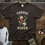 Torque Queen Shirt with vintage cartoon design of a girl holding a wrench on a brown background.