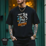 Trust Me I’m Almost a Doctor for Cars | Funny Mechanic T-Shirt worn by a person outdoors in a modern setting.