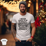 Man wearing the World’s Greatest Mechanic Shirt featuring a bold statement print in a festive outdoor setting.