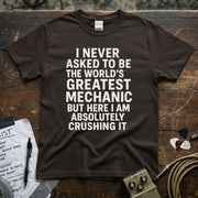 Brown shirt with text reading 'I Never Asked to Be the World’s Greatest Mechanic but Here I Am Absolutely Crushing It'.