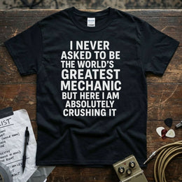 World’s Greatest Mechanic Shirt displayed on a wooden surface with text saying I never asked to be the world's greatest mechanic.